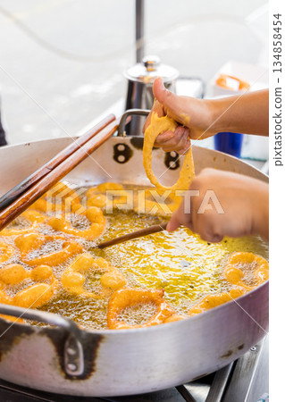 A woman is cooking picarones in a pan. 134858454