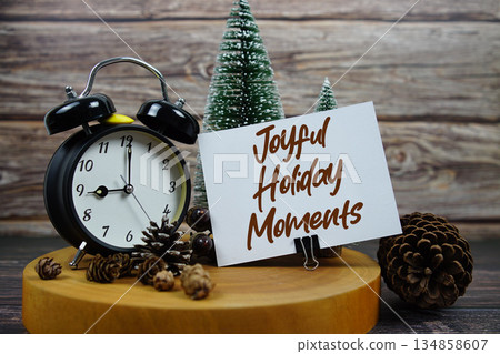 Festive holiday scene featuring a vintage alarm clock, pinecones, and miniature Christmas trees on a wooden base, with the text "Joyful Holiday Moments" encouraging support for local businesses during 134858607
