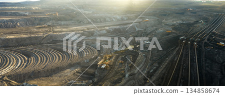 Aerial view of an active coal mining site showcases heavy machinery and smoke billowing into the air 134858674