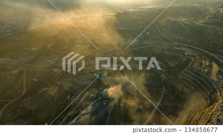 Aerial view of an active coal mining site showcases heavy machinery and smoke billowing into the air Aerial view of an active coal mining site showcases heavy machinery and smoke billowing into the air 134858677
