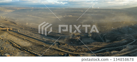 Aerial view of an active coal mining site showcases heavy machinery and smoke billowing into the air 134858678