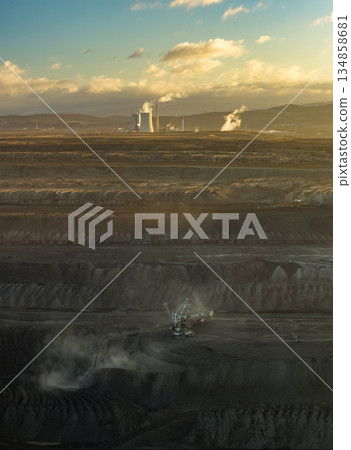 Aerial view of an active coal mining site showcases heavy machinery and smoke billowing into the air Aerial view of an active coal mining site showcases heavy machinery and smoke billowing into the air 134858681