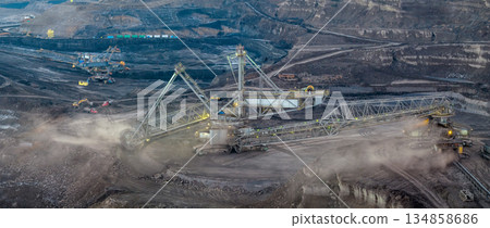 Aerial view of an active coal mining site showcases heavy machinery and smoke billowing into the air 134858686
