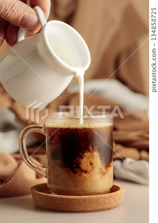 Pouring cream in black coffee. 134858725