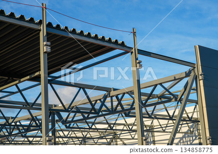 Steel roof and sandwich panel wall assembly on modern industrial warehouse construction site 134858775