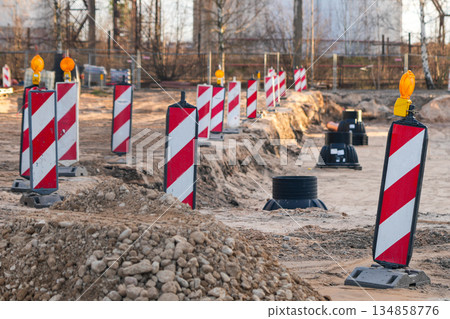 Red-white warning barriers at active construction site excavation zone during infrastructure work 134858776
