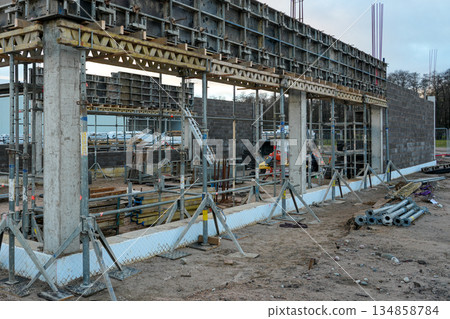 Concrete commercial building under construction with scaffolding, formwork, and support beams on site 134858784