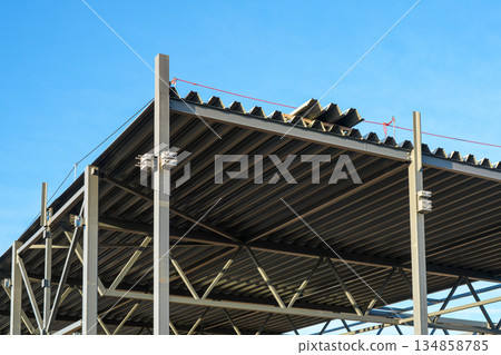 Steel building roof structure during construction with metal beams and corrugated roofing sheets 134858785