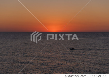 A boat cruising on calm sea at dawn or dusk. A boat cruising on calm sea at dawn or dusk. 134859135