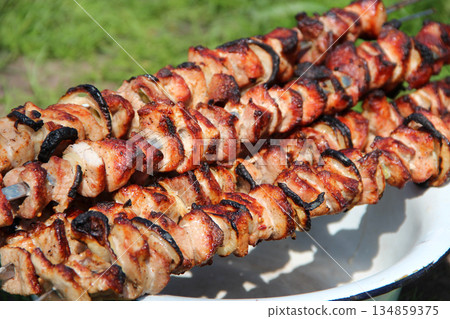 Appetizing shashlik on skewers on plate. Cooked pork meat. Barbecue lunch Appetizing shashlik on skewers on plate. Cooked pork meat. Barbecue lunch 134859375