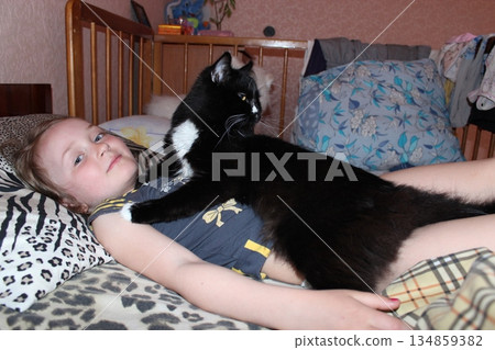Little girl laying in bed together with her cat. Together with your pet Little girl laying in bed together with her cat. Together with your pet 134859382