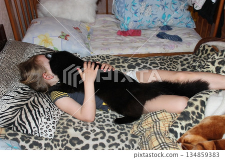 Little girl laying in bed together with her cat. Together with your pet Little girl laying in bed together with her cat. Together with your pet 134859383