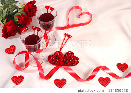 Two glasses of red wine on a festive table with roses, hearts, and a ribbon. Valentine's Day concept, advertising for a bar and cafe. Banner for an invitation to a festive buffet, card for a wedding, Two glasses of red wine on a festive table with roses, hearts, and a ribbon. Valentine's Day concept, advertising for a bar and cafe. Banner for an invitation to a festive buffet, card for a wedding, 134859928