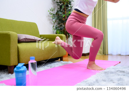 Bulgarian squat: A young woman wearing yoga wear and training her lower body indoors, hip-up Bulgarian squat: A young woman wearing yoga wear and training her lower body indoors, hip-up 134860496