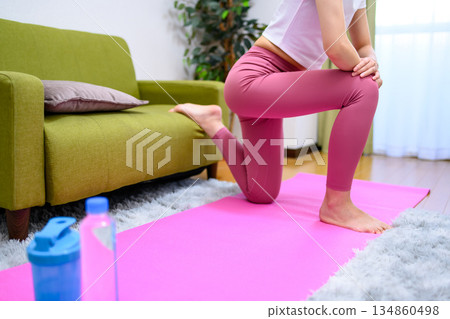 Bulgarian squats: Young woman wearing yoga wear training her lower body indoors, buttocks up, tough, rest Bulgarian squats: Young woman wearing yoga wear training her lower body indoors, buttocks up, tough, rest 134860498