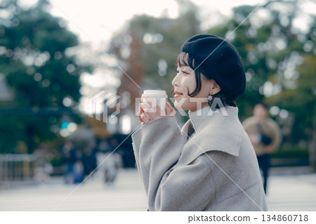 Full body lifestyle of a woman in her 30s sitting outdoors and drinking coffee Full body lifestyle of a woman in her 30s sitting outdoors and drinking coffee 134860718