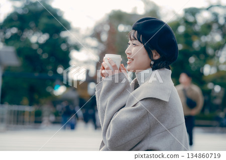 Full body lifestyle of a woman in her 30s sitting outdoors and drinking coffee Full body lifestyle of a woman in her 30s sitting outdoors and drinking coffee 134860719