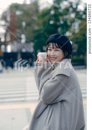 一位30多歲的女性坐在戶外喝咖啡的全身照,展現了她豐富多彩的生活方式。 一位30多歲的女性坐在戶外喝咖啡的全身照,展現了她豐富多彩的生活方式。 134860720