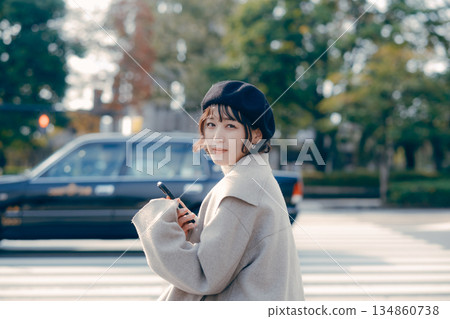 一位三十多歲的女性坐在戶外，看著她的智慧型手機，展現了她的生活方式。 134860738