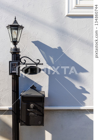 古色古香的門柱和郵箱在牆上投下令人印象深刻的陰影。 134860744