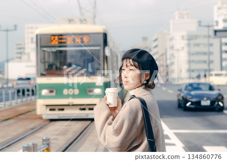 一位三十多歲的女性在車站月台上喝咖啡的生活場景 一位三十多歲的女性在車站月台上喝咖啡的生活場景 134860776