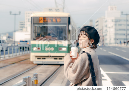 一位三十多歲的女性在車站月台上喝咖啡的生活場景 一位三十多歲的女性在車站月台上喝咖啡的生活場景 134860777
