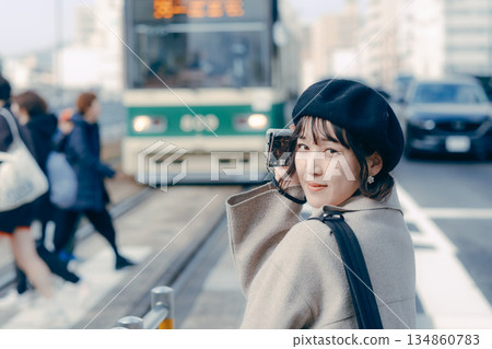 Portrait of a woman in her 30s smiling and holding a camera Portrait of a woman in her 30s smiling and holding a camera 134860783