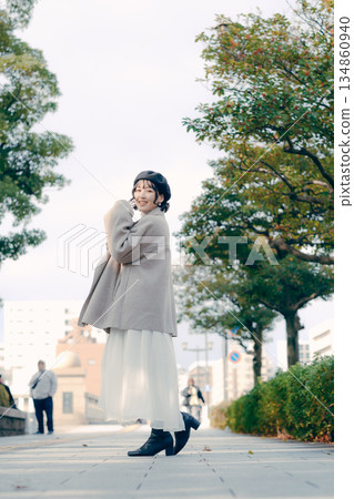 Full-body portrait of a woman in her 30s carrying a coffee cup at a tourist spot Full-body portrait of a woman in her 30s carrying a coffee cup at a tourist spot 134860940