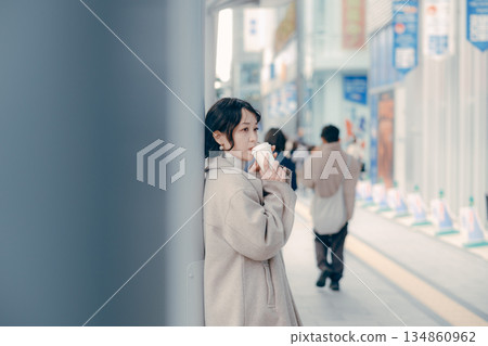 一位三十多歲的女性在公車站等車時喝咖啡的肖像 一位三十多歲的女性在公車站等車時喝咖啡的肖像 134860962