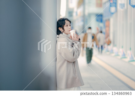 一位三十多歲的女性在公車站等車時喝咖啡的肖像 134860963