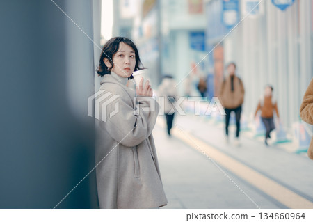 一位三十多歲的女性在公車站等車時喝咖啡的肖像 134860964