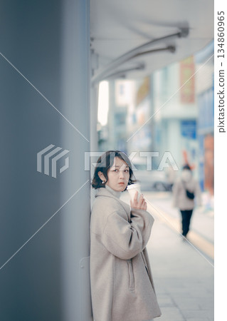 一位三十多歲的女性在公車站等車時喝咖啡的肖像 一位三十多歲的女性在公車站等車時喝咖啡的肖像 134860965