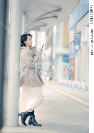 一位三十多歲的女性在公車站等車時喝咖啡的肖像 134860972