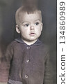 A vintage portrait of a cute three-year-old boy, looking at something with wide eyes and surprise. Retro photo from the 1970s. 134860989