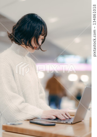 一名三十多歲的女子在城市裡操作筆記型電腦 134861018