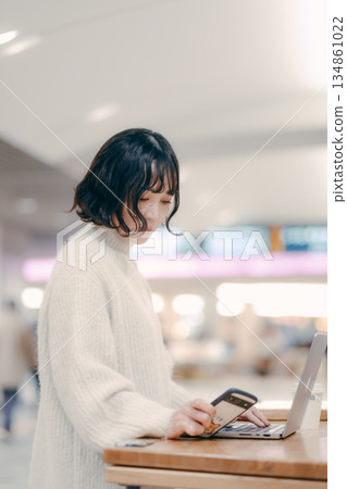 一名三十多歲的女子在城市裡操作筆記型電腦 一名三十多歲的女子在城市裡操作筆記型電腦 134861022