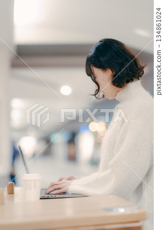 一名三十多歲的女子在城市裡操作筆記型電腦 一名三十多歲的女子在城市裡操作筆記型電腦 134861024