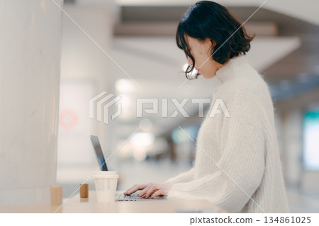 一名三十多歲的女子在城市裡操作筆記型電腦 一名三十多歲的女子在城市裡操作筆記型電腦 134861025