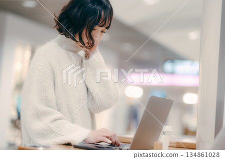 A woman in her 30s operating a laptop in the city 134861028