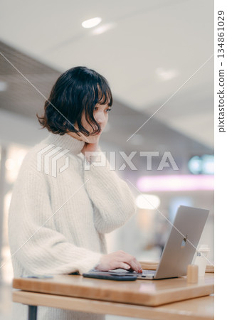 A woman in her 30s operating a laptop in the city 134861029