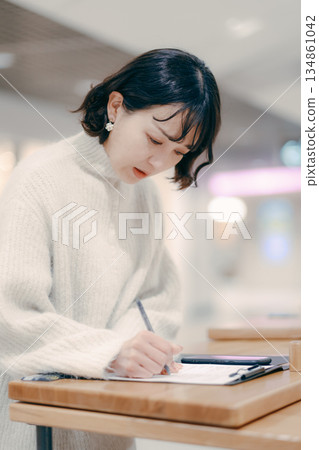 A woman in her 30s working while writing notes in the street A woman in her 30s working while writing notes in the street 134861042