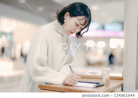 一位三十多歲的女子在街上邊工作邊寫筆記 一位三十多歲的女子在街上邊工作邊寫筆記 134861044