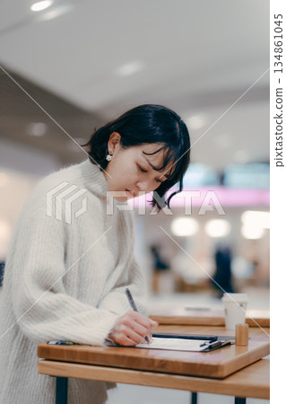 A woman in her 30s working while writing notes in the street 134861045