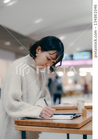 A woman in her 30s working while writing notes in the street 134861046