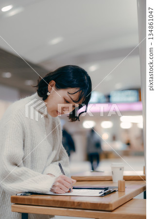 A woman in her 30s working while writing notes in the street A woman in her 30s working while writing notes in the street 134861047