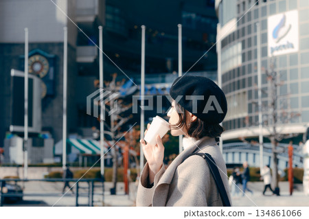 一位三十多歲的女子手捧一杯咖啡在鎮上閒晃。 134861066