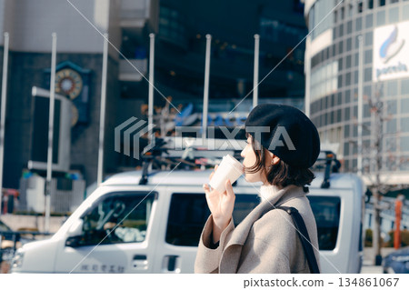 一位三十多歲的女子手捧一杯咖啡在鎮上閒晃。 134861067