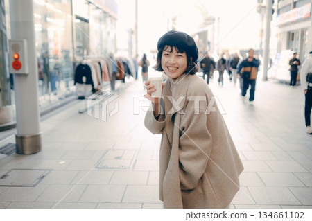 A woman walking in the city with a cup of coffee 134861102