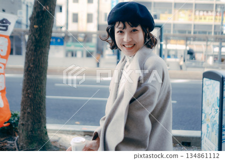 A woman walking in the city with a cup of coffee 134861112