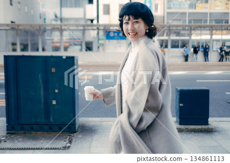 A woman walking in the city with a cup of coffee 134861113